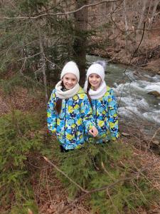two girls are standing next to a river at Sadyba Lukacha in Zhdenievo