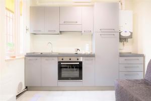 Centro Storico Oltretorrente Apartment في بارما: مطبخ ابيض مع دواليب بيضاء وفرن