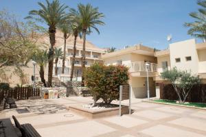 a building with palm trees and a sign in a courtyard at HI - Ein Gedi Hostel in Ein Gedi