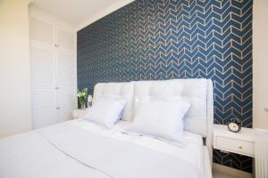 a bedroom with a white bed with a blue accent wall at Apart Harmony - Apartament Hampton in Puck