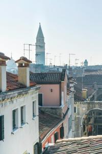 einen Blick auf die Dächer von Gebäuden mit einem Uhrturm in der Unterkunft Rialto Canal View With Terrace and Balcony by Wonderful Italy in Venedig