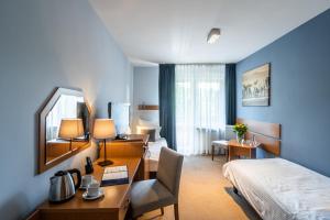 ein Hotelzimmer mit einem Bett, einem Schreibtisch und einem Schlafzimmer in der Unterkunft Hotel Nawigator Szczawnica in Szczawnica