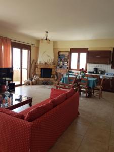 a living room with two red couches and a kitchen at Villa Ikarus in Triopetra