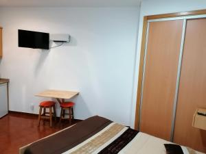 ナザレにあるEstúdio - Nazaréのベッドルーム1室(ベッド1台、テーブル、スツール2脚付)