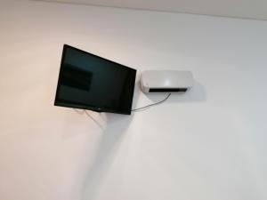 a television and a printer on a white wall at Estúdio - Nazaré in Nazaré