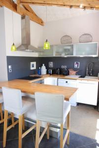 Una cocina con una mesa de madera y sillas blancas. en La Siesta, en La Rochelle