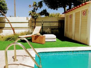 une piscine avec une chaise et une valise à côté d'une clôture dans l'établissement TripGeo Pinhal da Aroeira Villa, à Almada