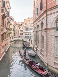 Un gruppo di persone che cavalca in una gondola lungo un canale di San Marco Square with Canal View by Wonderful Italy a Venezia