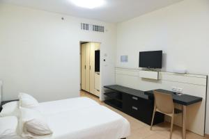 a bedroom with a bed and a desk with a television at HI - Karei Deshe Hostel in Khirbet Minim