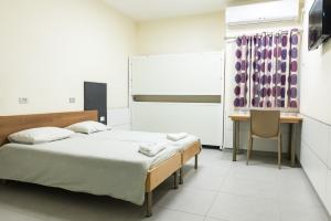 a bedroom with two beds and a desk and a table at HI - Tel Hai Hostel in Tel H̱ay