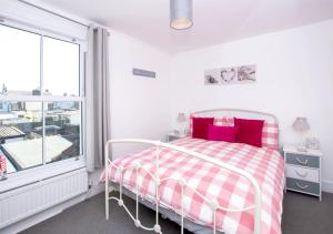 Schlafzimmer mit einem rosa und weißen Bett und einem Fenster in der Unterkunft Seashell Cottage in Deal