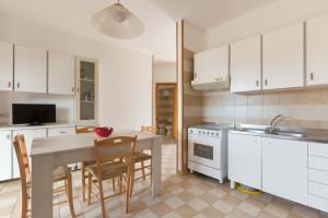 a kitchen with white cabinets and a table with chairs at Casa Di Ronzino by BarbarHouse in San Foca