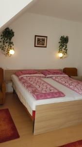 a bedroom with a large bed with pink sheets at Pension Óvári in Bük