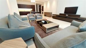 Eden Garden Hotel Apartment في المنامة: غرفة معيشة مع أريكة وكراسي وطاولة