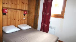 a bedroom with a bed with two pillows and a window at La Dame Blanche - Cimes et Neige in Puy-Saint-Vincent