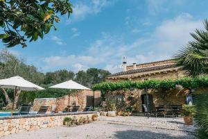 a stone house with a swimming pool and umbrella at The Old Cottage in Sencelles