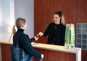 een vrouw die de hand schudt met een vrouw aan de balie bij Haus am See - Gochness in Kessel