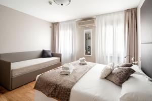 Habitación blanca con cama y sofá en Locanda Herion, en Venecia