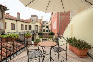 una mesa y sillas en un balcón con sombrilla en Locanda Herion, en Venecia