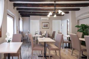 Un comedor con mesas y sillas blancas. en Locanda Herion, en Venecia