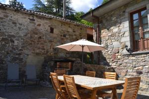 una mesa de madera con una sombrilla frente a un edificio en Casas Rurales Las Corradas, en Éndriga