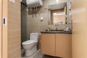 a bathroom with a toilet and a sink and a mirror at Foshan Laide Apartment in Shunde