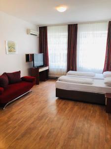 um quarto com uma cama e um sofá vermelho em Hotel Verdi em Munique