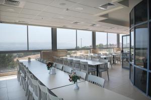 a dining room with tables and chairs and large windows at HI - Beit Shean Hostel in Bet Sheʼan