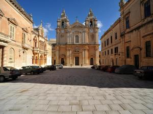 a large building with a clock tower in a street at The Xara Palace Relais & Chateaux in Mdina