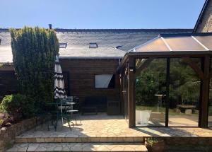 a patio with an open door and an umbrella at Gîte La Maison d'Amélie in La Chapelle-Saint-Aubert