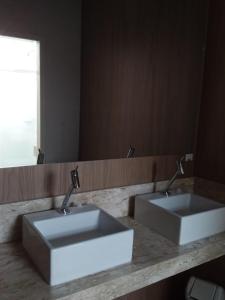 a bathroom with two sinks in front of a mirror at CHA Mime Hotel in Blumenau