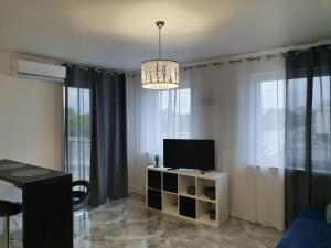 a living room with a television and a chandelier at Apartament na Lazurowej in Warsaw