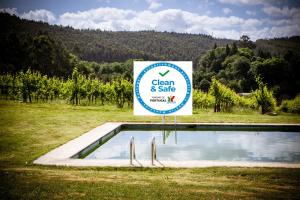 a sign next to a swimming pool in a field at Quinta de Lourosa in Lousada