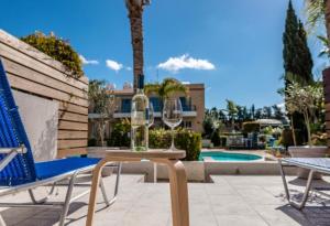 eine Terrasse mit einem Tisch, Stühlen und einem Pool in der Unterkunft Holiday Cosy Home in Paphos City