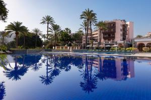 a pool at a resort with palm trees and buildings at Santa Catalina, a Royal Hideaway Hotel in Las Palmas de Gran Canaria