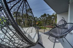 a swing on a balcony with a bed and a chair at Baltic Apartments in Pobierowo