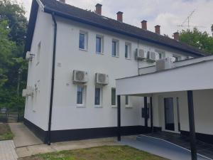 un edificio blanco con ventanas y techo en Kid Família Panzió Balatonszárszó en Balatonszárszó