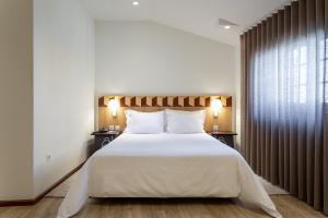 a bedroom with a large bed with white sheets and pillows at Hotel Aveiro Center by Alboi Group in Aveiro +42 photos