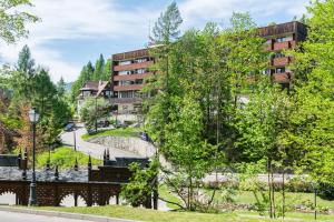 a building with a bridge and trees in front of it at Hotel Nawigator Szczawnica in Szczawnica