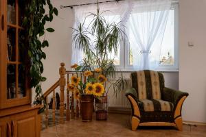 una sala de estar con una silla y un jarrón de flores en Agroturystyka Gawryś pokoje en Sasino
