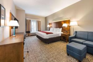 a hotel room with a bed and a couch and a chair at Comfort Inn Grove City - Columbus South in Grove City