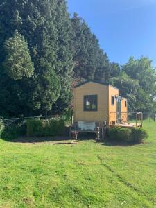 a small yellow trailer in a field with trees at Joly Tiny House in Overijse