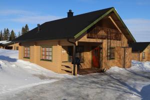 Cabaña de madera con puerta roja en la nieve en Matkailumaja Heikkala Cottages en Ruka