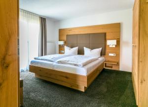 Schlafzimmer mit einem großen Bett mit einem Kopfteil aus Holz in der Unterkunft Hotel-Restaurant Sennhütte im Herzen des Südschwarzwalds in Kleines Wiesental