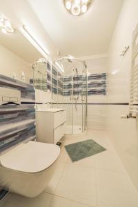 a white bathroom with a tub and a toilet at Baltic Apartments in Pobierowo