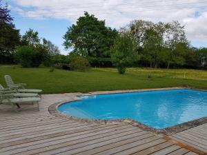 a swimming pool on a wooden deck next to a yard at Les Roberderies in Broc
