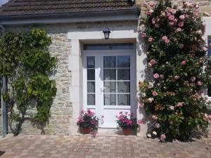 a white door with flowers on a stone house at Chambres d'Hotes Elvire et Laurent Barbey in Sainte-Marie-du-Mont
