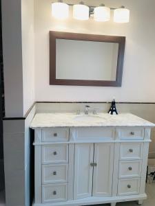 La salle de bains est pourvue d'un lavabo blanc et d'un miroir. dans l'établissement Boston Lodge and Suites, à Boston