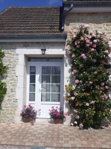 a house with a white door with roses on it at Chambres d'Hotes Elvire et Laurent Barbey in Sainte-Marie-du-Mont