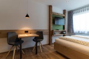 a bedroom with a bed and a desk and two chairs at Ferienwohnung Paulus in Oberstdorf